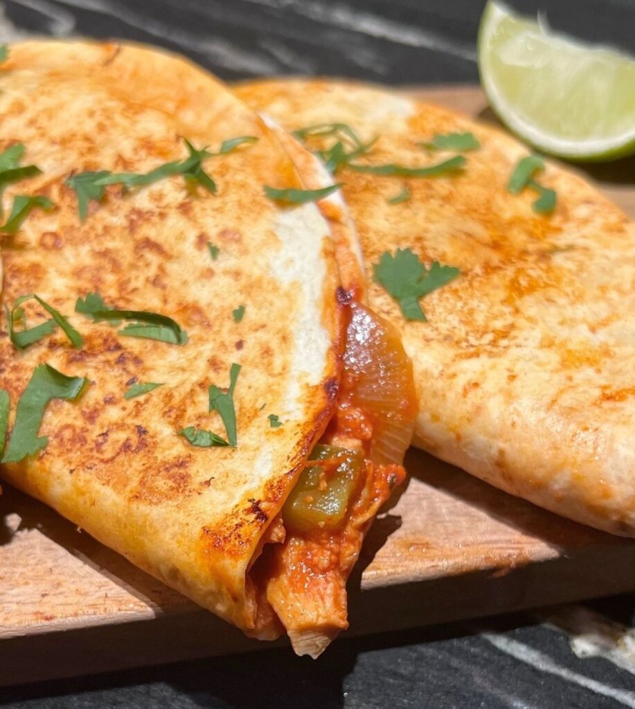 Close-up shot of a pulled chicken taco filled with shredded chicken, cheese, and sauce.