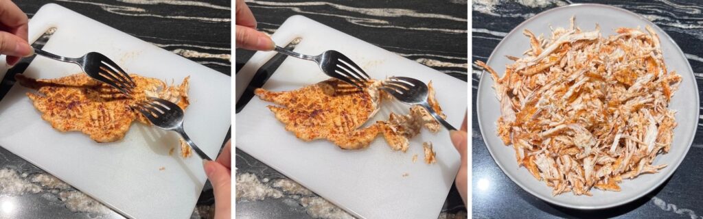 Shredded chicken being pulled apart with two forks on a plate.