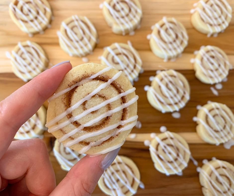 Close-up of a cinnamon roll cookie with icing drizzle, showing its detailed cinnamon swirl and soft texture