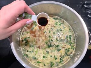 making dumpling soup in pot including adding soy sauce