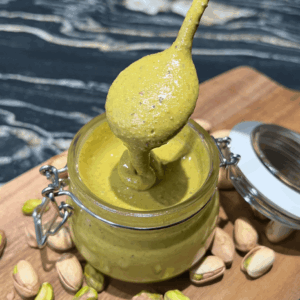 pistachio cream in a jar with a spoon showing the smooth texture
