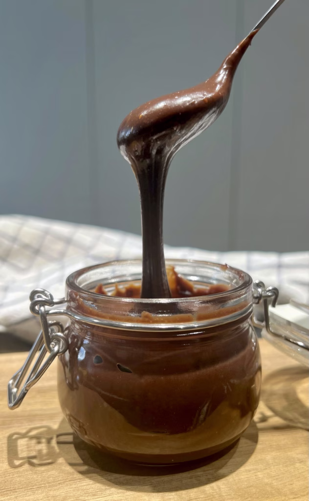 Chocolate fudge sauce in a jar with a spoon drizzling