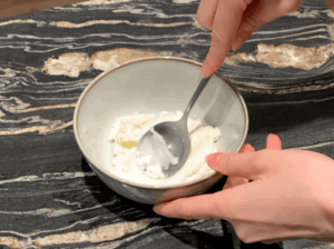 Softening cream cheese in a bowl with a spoon to make a smooth ice cream base