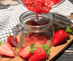 transferring strawberry jam to a jar while still hot after making strawberry jam at home