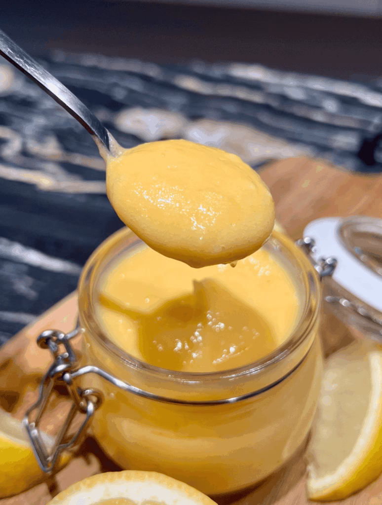Jar of homemade lemon curd with a spoon to show texture