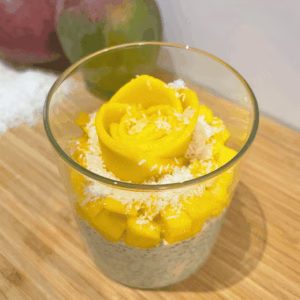 Mango chia pudding topped with a flower design made from thin mango slices, served in a jar glass.