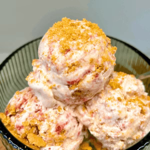 Close-up of creamy strawberry cheesecake ice cream with swirls of strawberry jam and cookie crumbs