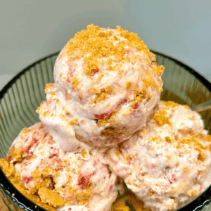 Close-up of creamy strawberry cheesecake ice cream with swirls of strawberry jam and cookie crumbs