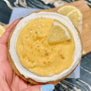 Close-up of a hand holding a full lemon cheesecake cookie