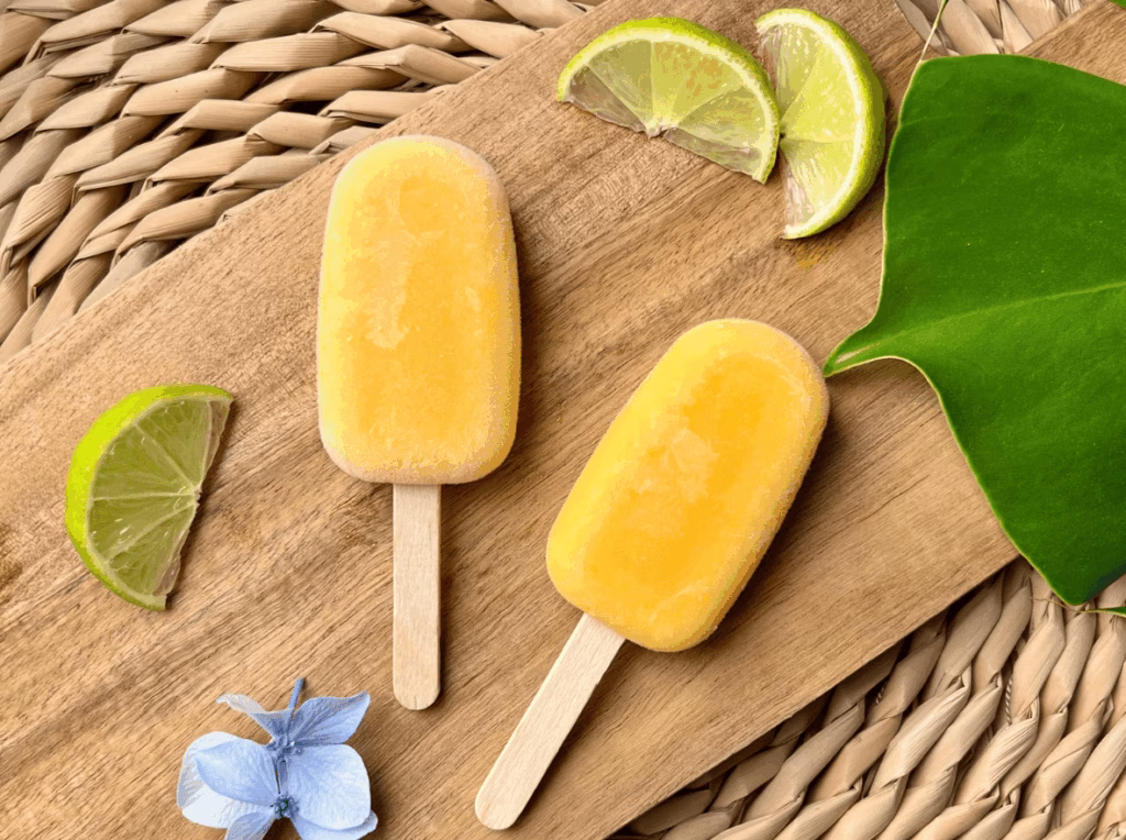 Two easy mango sherbet popsicles on a board ready to eat