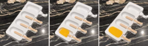 Mango sherbet poured into popsicle molds with sticks inserted before freezing