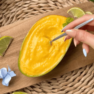 Scooping homemade mango sherbet from a mango shell