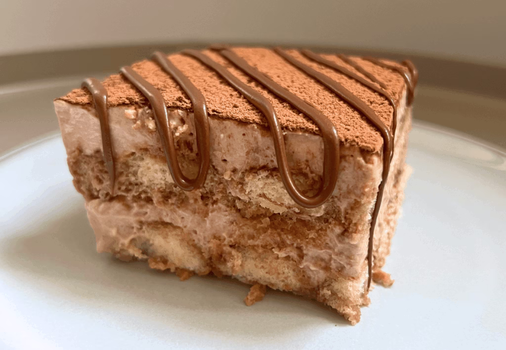 A slice of Nutella tiramisu on a plate with Nutella drizzled on top