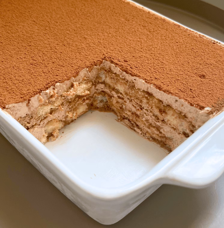 The tiramisu dish with a missing slice, revealing creamy layered insides