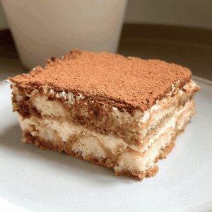 Slice of easy tiramisu on a plate with cocoa on top