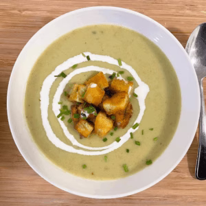 Bowl of leek and potato soup with thyme and toasted bread for garnish.