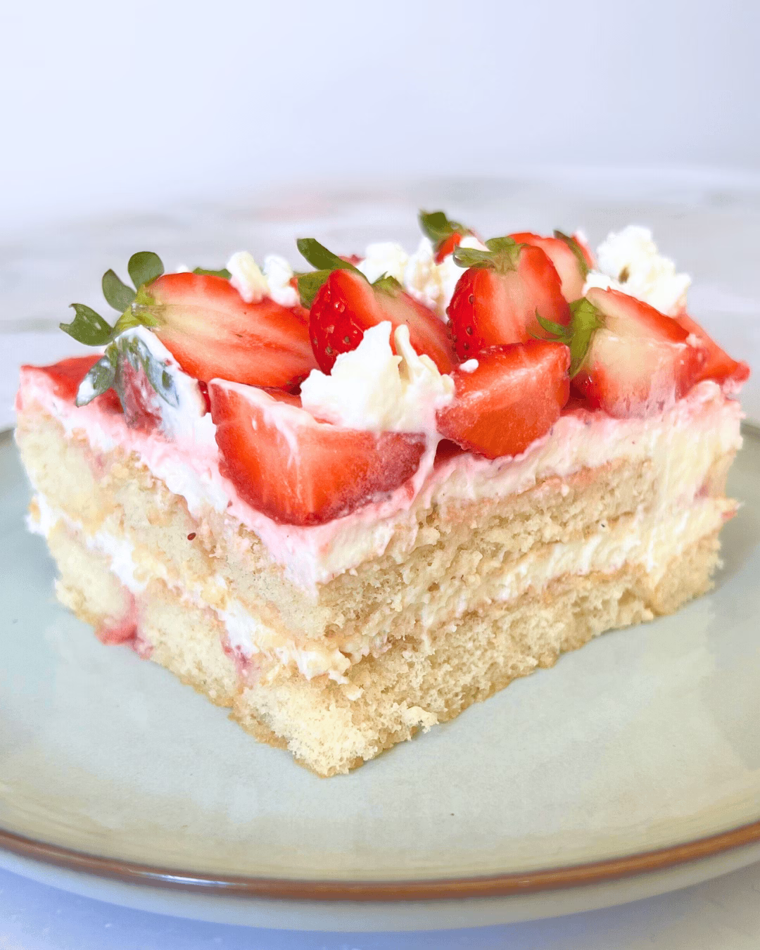 Creamy slice of strawberry tiramisu showing layers of mascarpone, ladyfingers, and strawberry puree.