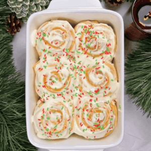 sugar cookie cinnamon rolls in a dish topped with cream cheese glaze and sprinkles