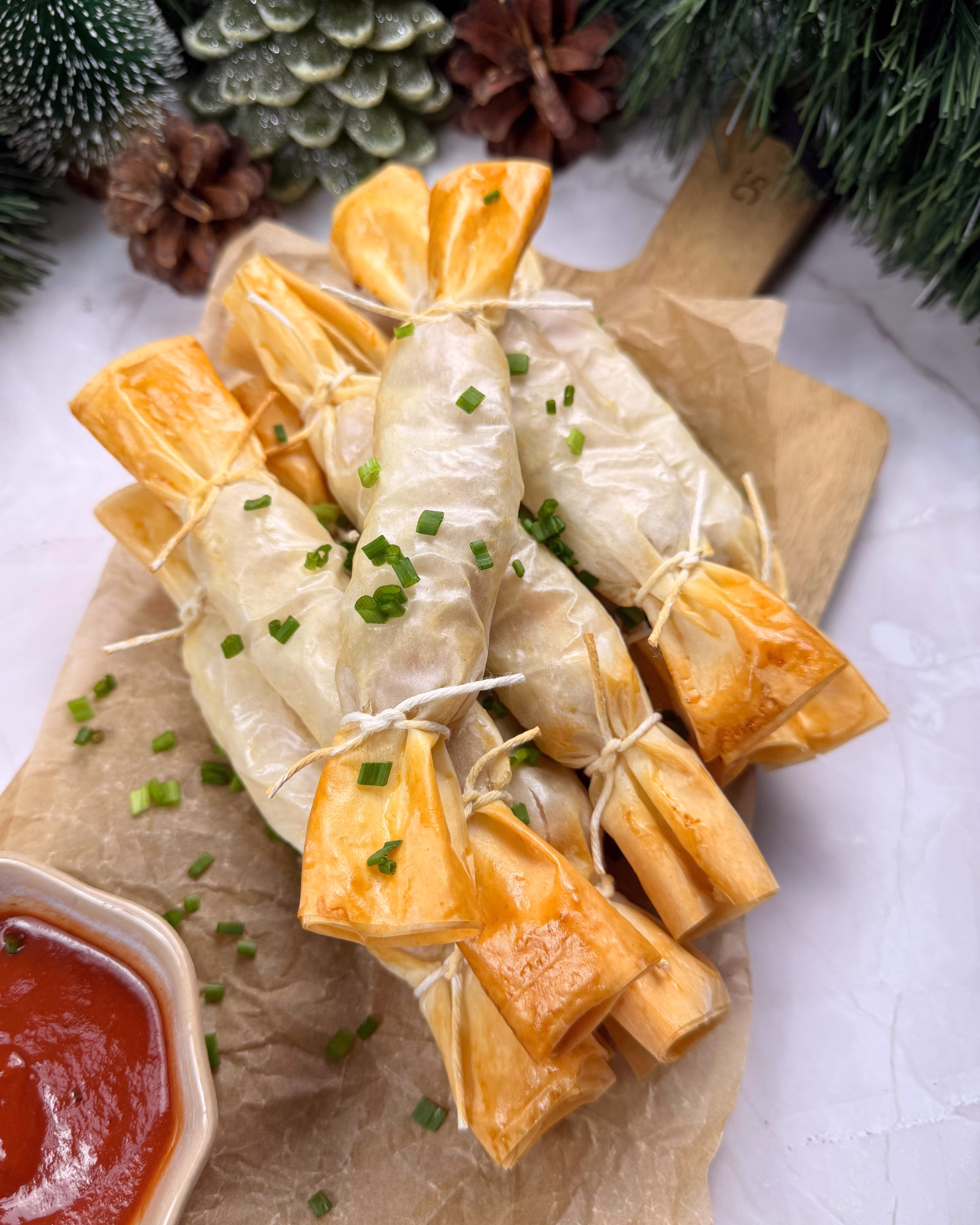 Cheesy phyllo hot dog crackers arranged on a plate shaped like Christmas crackers.