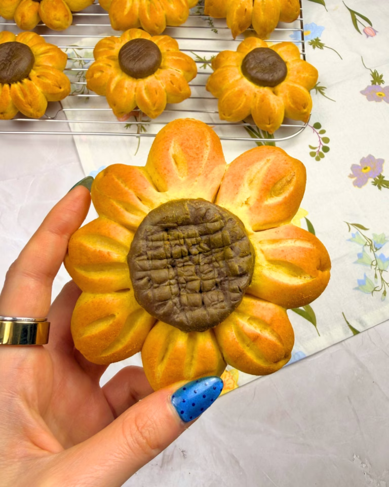 Close-up of a hand holding a golden turmeric sunflower brioche.