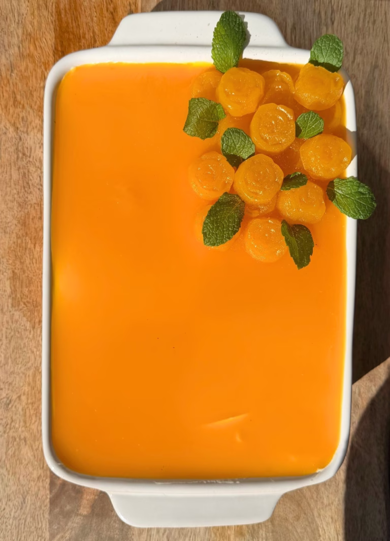 Top view of yellow mango pulp spread over tiramisu in a dish