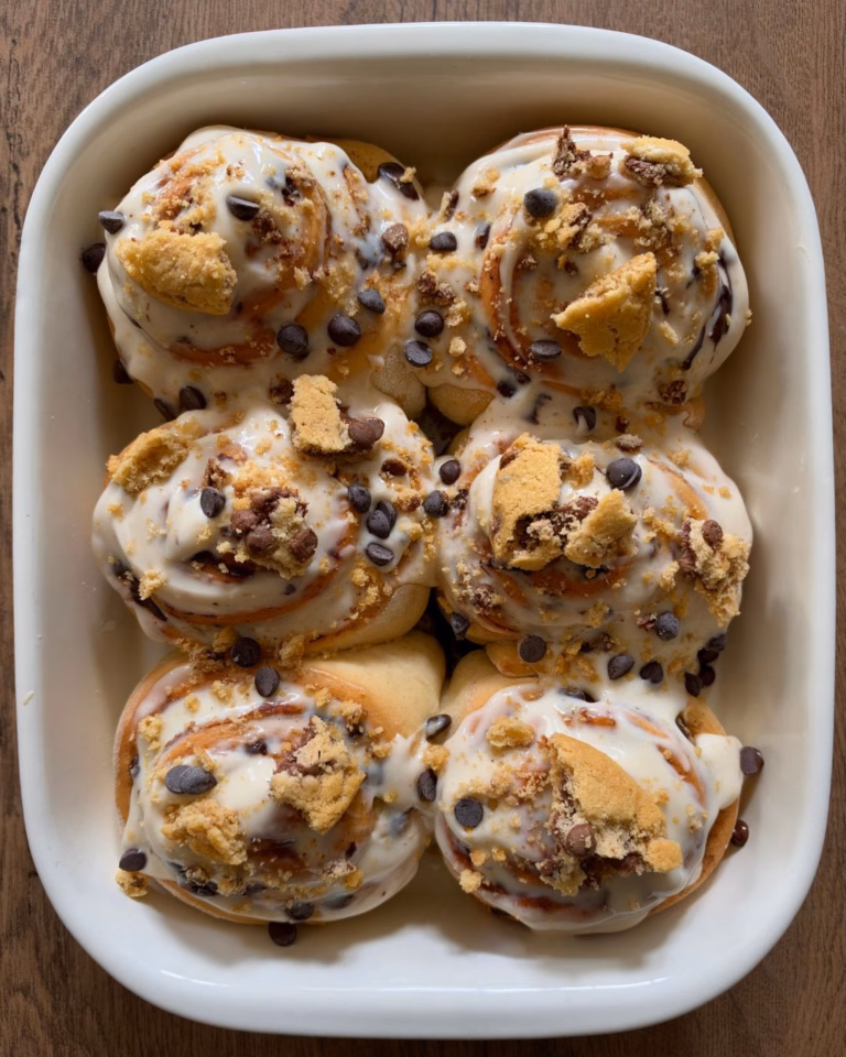 Freshly baked chocolate chip cinnamon rolls topped with cream cheese frosting and cookie crumbs.